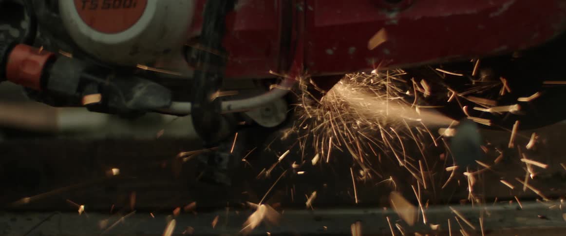 Sparks flying around a power saw cutting a piece of metal
