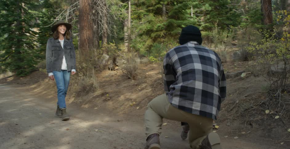 Mom smiles as she watches their baby girl run to her dad who is kneeling on the trail