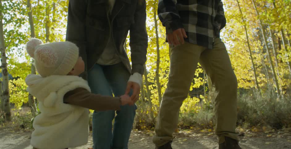 Mother walking in the forest with her family picks up her toddler daughter at morning