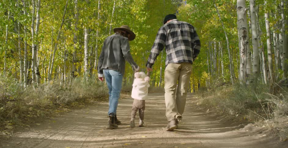 Mom and dad walking on a trail lifting their daughter up by the hands