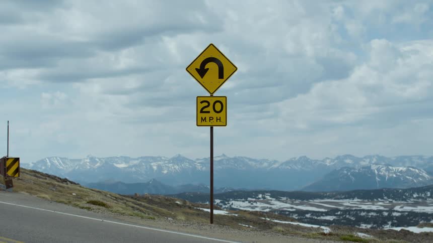 A street sign near a road is displayed in a rural area