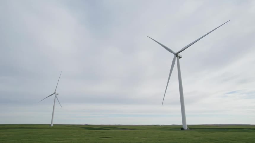 Two wind turbines on grass land under a cloudy sky