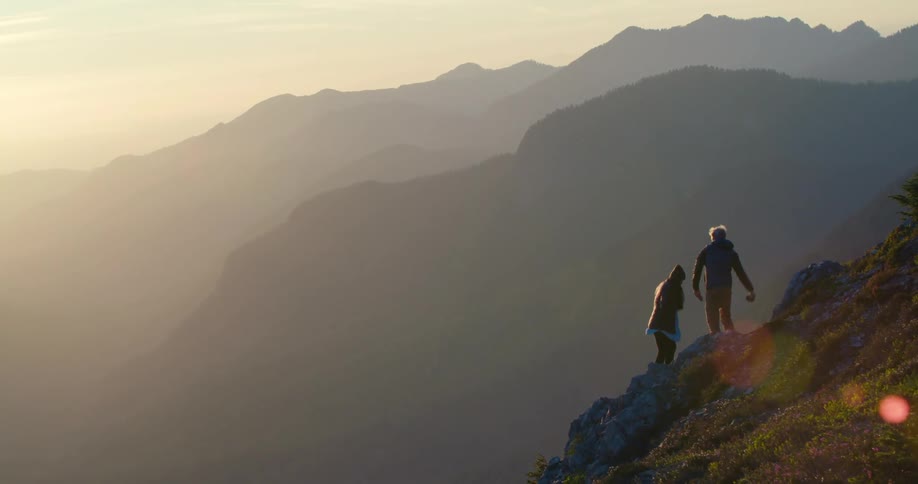 Two people are rock climbing while the sun is setting