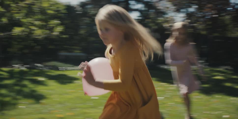 Kids race through a backyard chasing a boy with a balloon during a playful summer moment