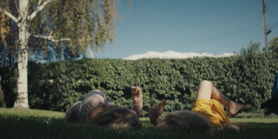 Two children are resting in the backyard during spring
