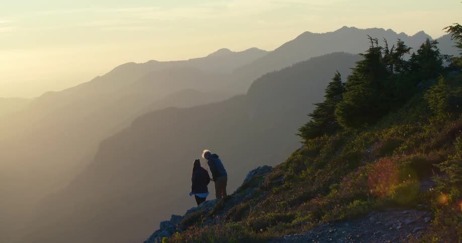A man and woman stand on the side of a mountain and take in the view