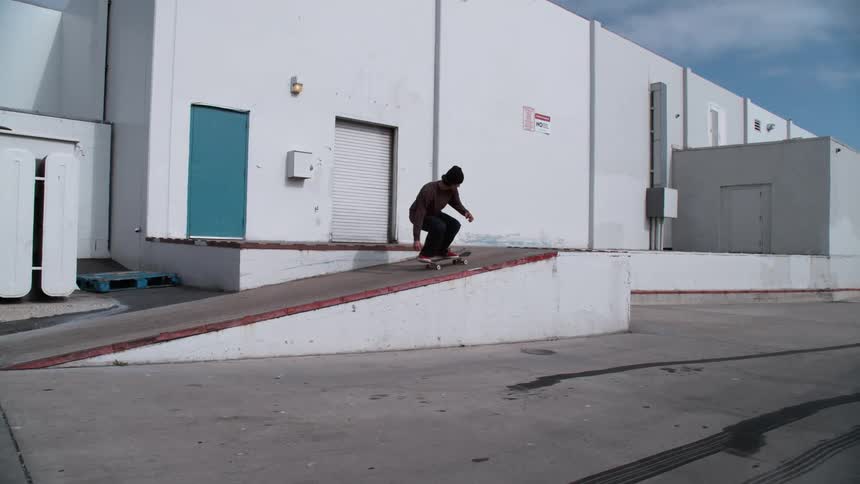 A man is skateboarding in an empty parking lot