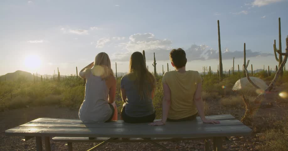 Three friends sitting on picnic bench in the desert enjoying the view