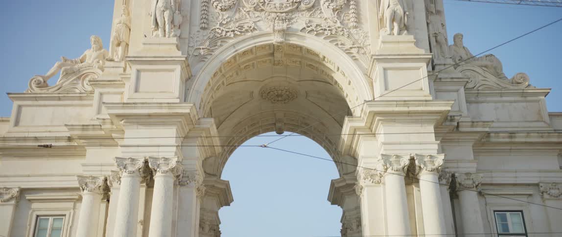 Tourists are visiting an archway landmark in a city during the daytime