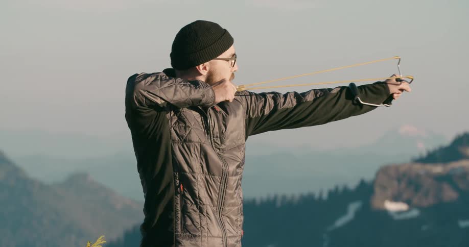 A man is outdoors and using a slingshot