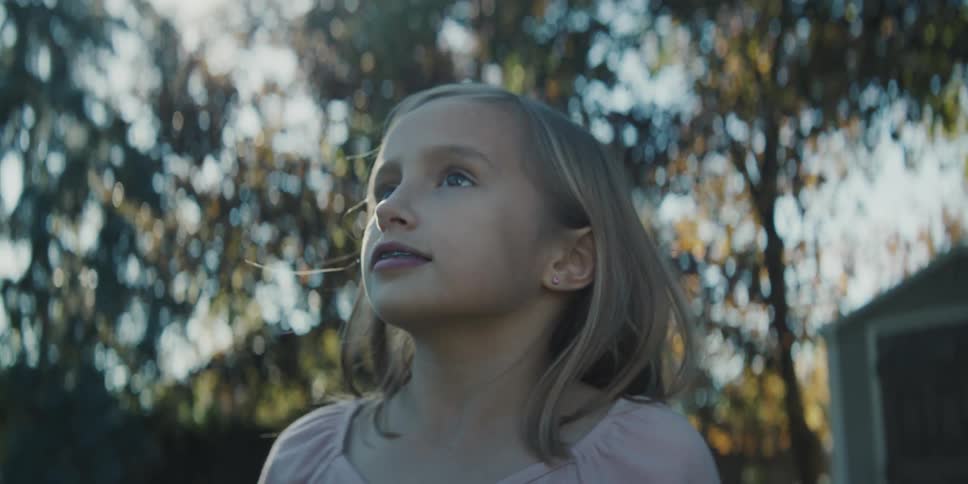 Blonde girl with pink blouse and dental brace smiles and looks around in the garden