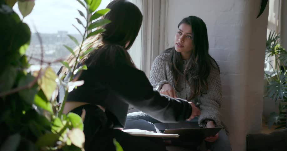 Two girls study next to a window