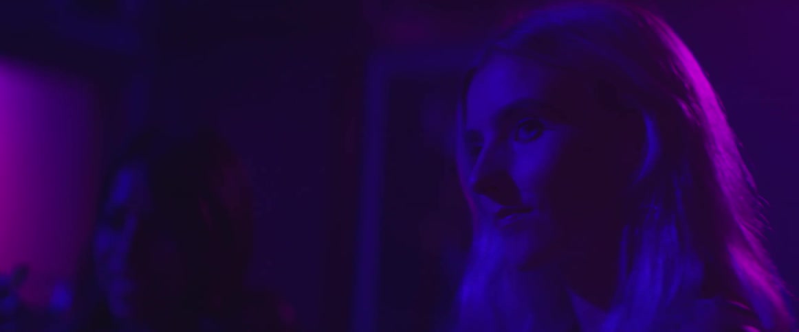 A woman is smiling in a dark club