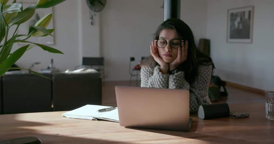 A woman sits at a table using a laptop