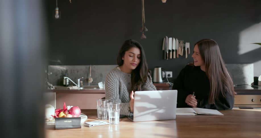 Two women are discussing something in the kitchen