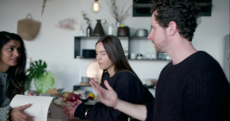 Three people talk while flipping through a book