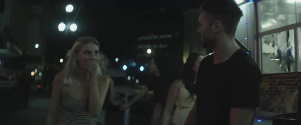 A group of people walk down the street at night