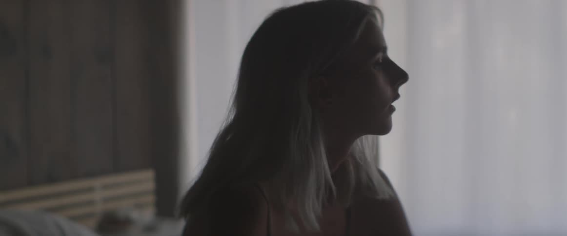 Blonde woman sitting in a room looking around