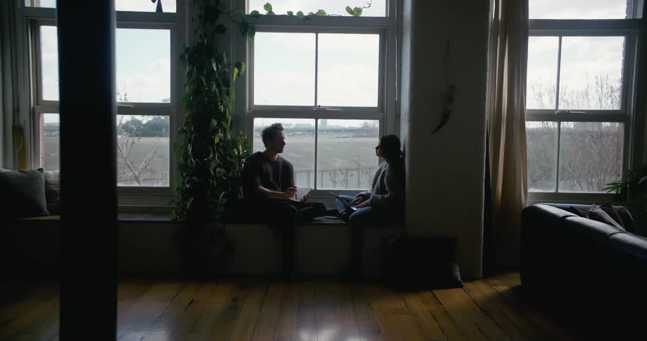 A couple sit facing each other in a window seat