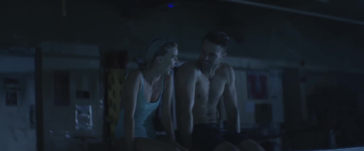 Man and woman sitting at edge of pool talking and laughing