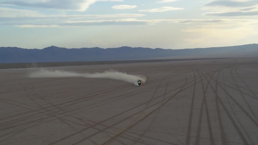 A motorcycle is driving in the desert