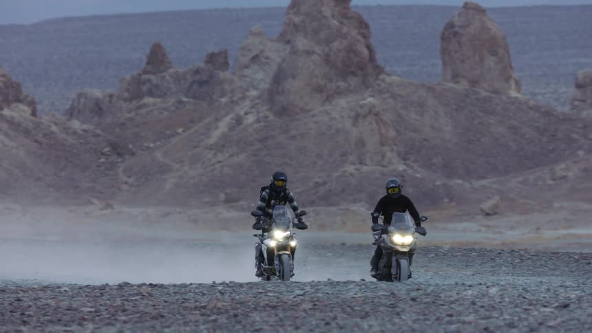 Bikers with black motorcycle helmet jacket ride motorcycles in desert at dusk