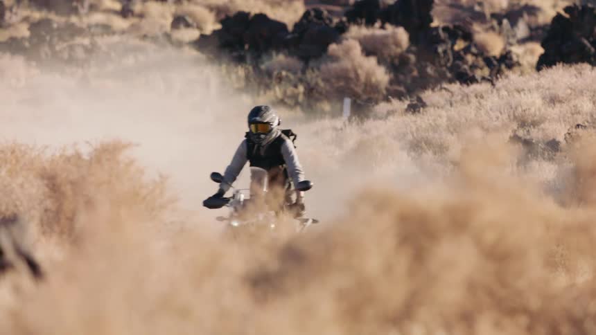 Two motorcyclists ride motorcycles in the grassy field