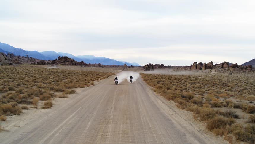 Aerial view of bikers riding motorcycles on dirt road in desert