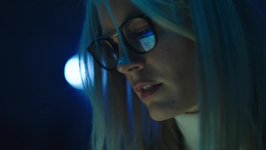 The reflection in a womans glasses shows her writing on a tablet