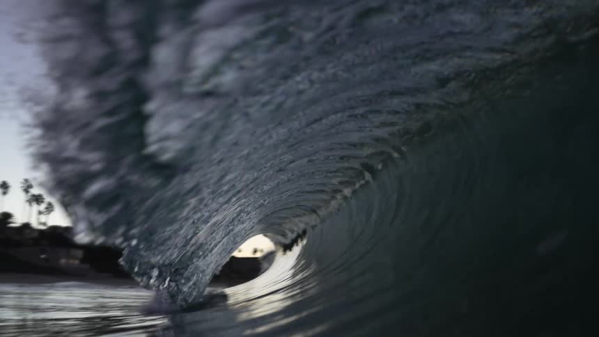 A huge wave rolls in splashing as it goes overhead and the view changes to underwater