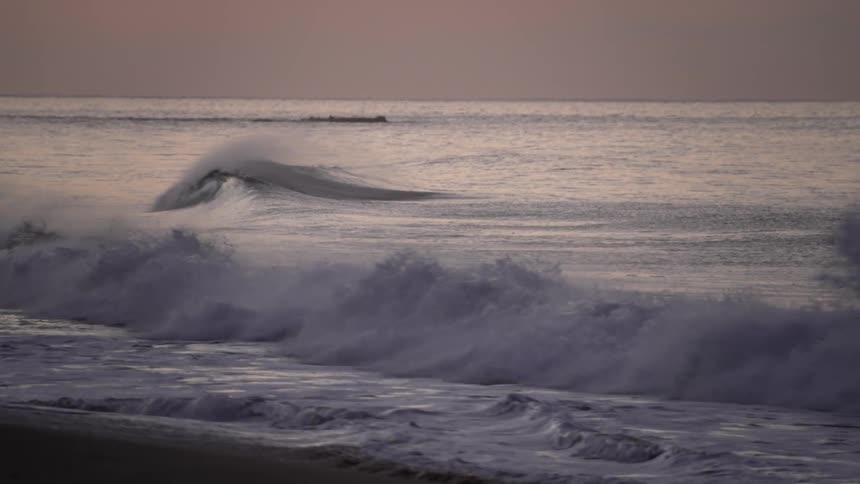 Waves roll in over a beach splashing as they move