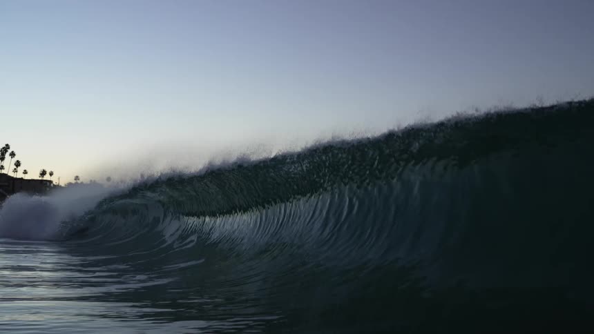 A large ocean wave crashes towards the shore