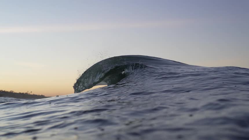 Waves are moving through the ocean at dusk