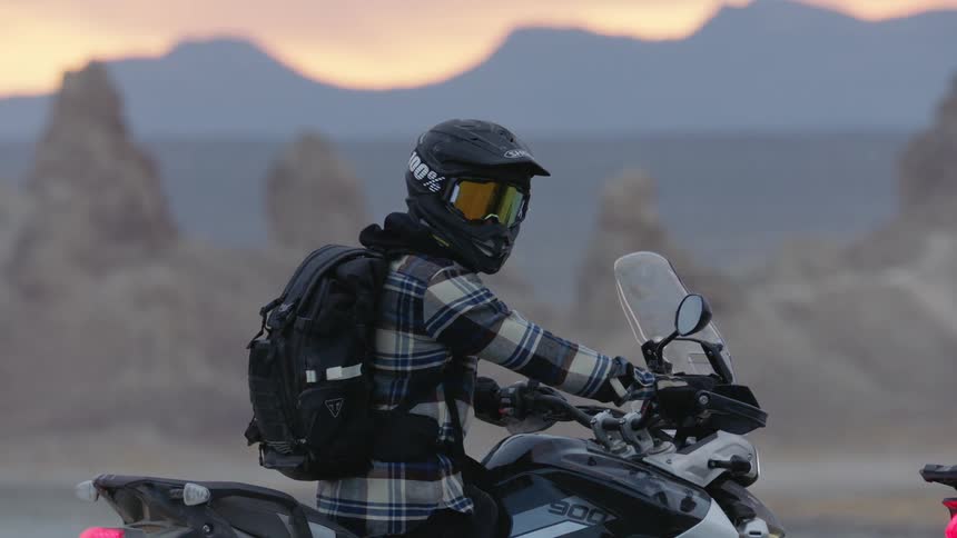 A person is sitting on a motorcycle in a rocky landscape