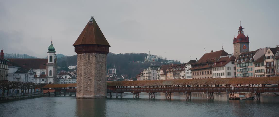 Bridge with tower over river between buildings and houses