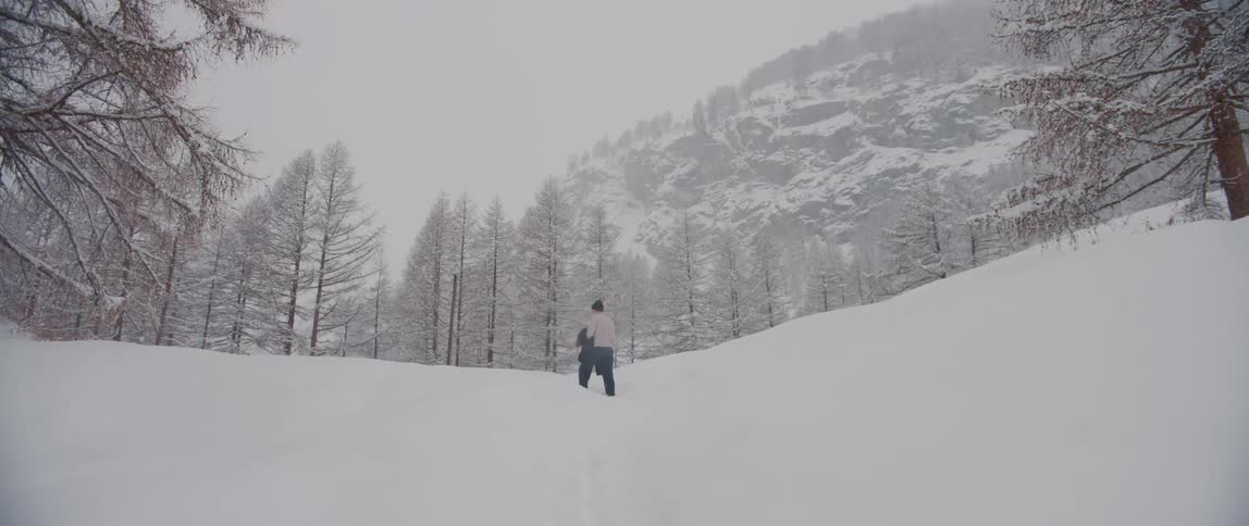 A man is walking through the deep snow