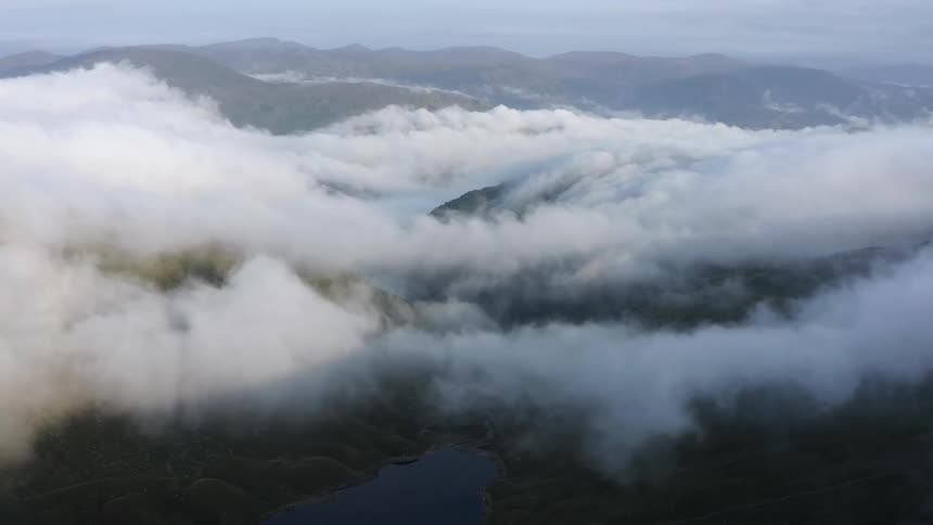 Aerial view of white clouds rolling over the mountain tops at morning