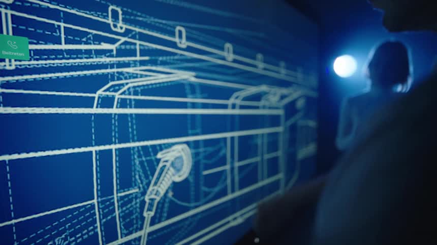 Man enlarges a diagram using his fingers on a large touch screen display as a woman watches
