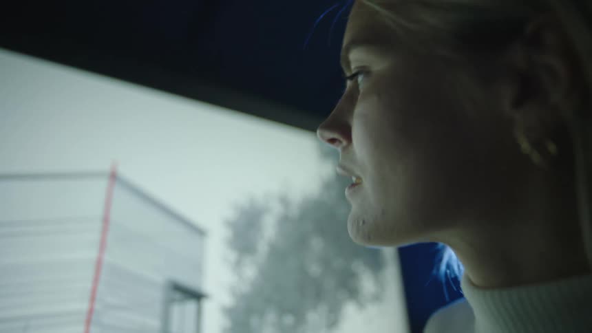 A woman in an office draws a red line on a picture of a building on a screen
