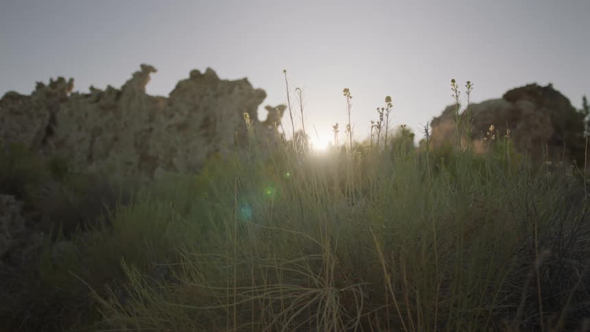 The sun shines behind hill slope with big rocks