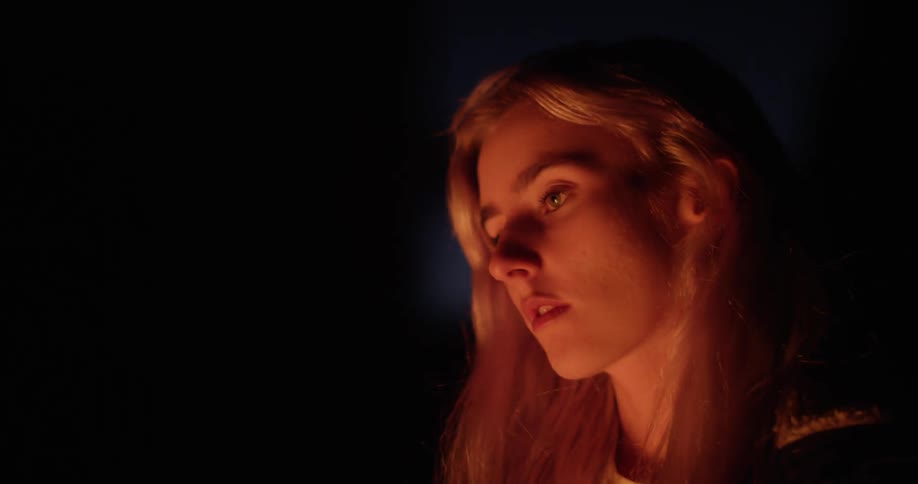 Woman's face lit up by the light of a fire at night