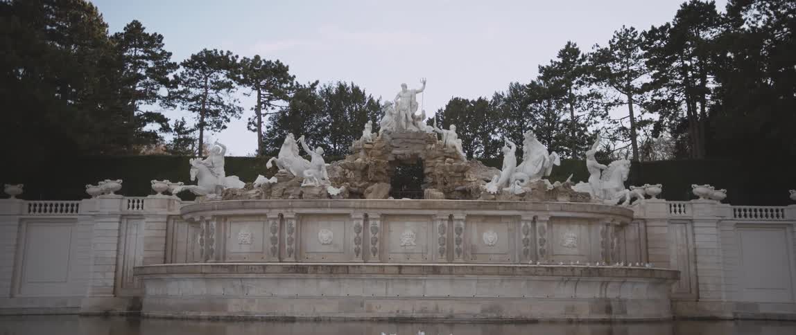 Monument with statues of men and horses sits near the trees