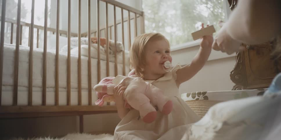 A woman and toddler play on a nursery floor