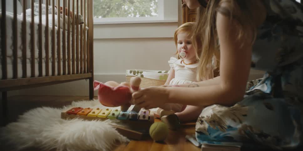 A woman plays with her daughter on the bedroom floor
