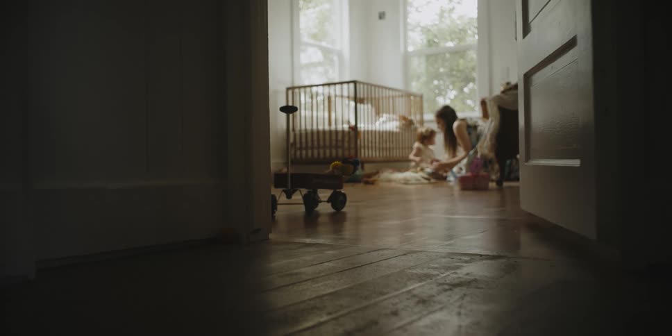 A woman sits on the floor with an infant girl