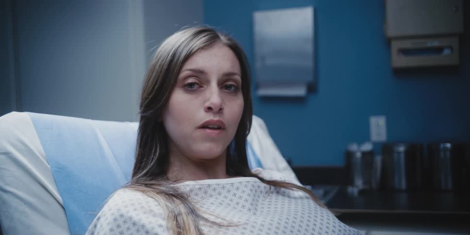 A woman in a hospital gown lays on an exam table