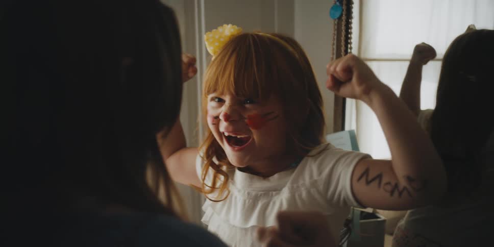 A girl flexes her muscles for her mom