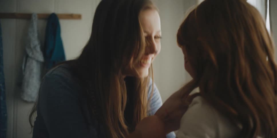A young girl plays with a woman wearing face paint