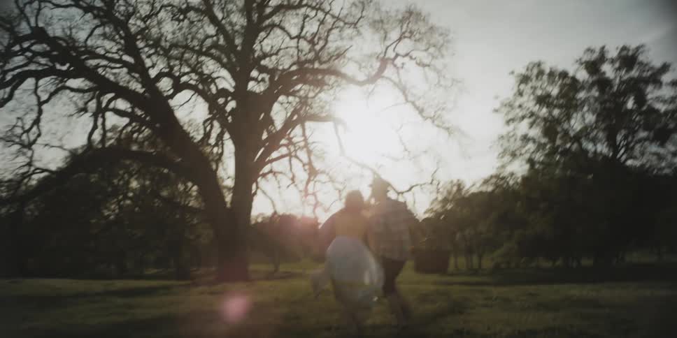 A couple run down a field holding hands