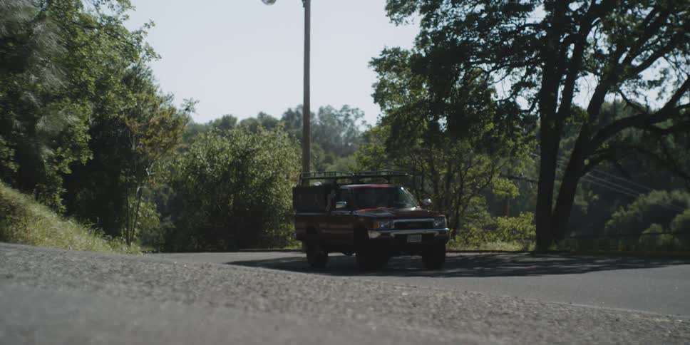 A pickup truck drives slowly over a bump in the road then stops